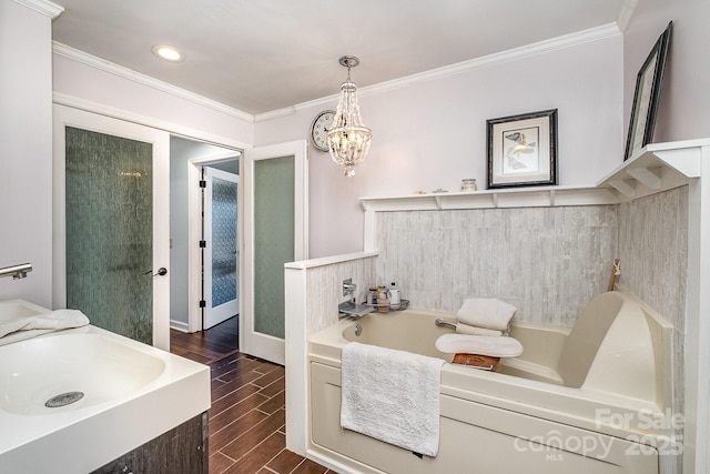 bathroom featuring a garden tub, ornamental molding, a sink, and wood finish floors