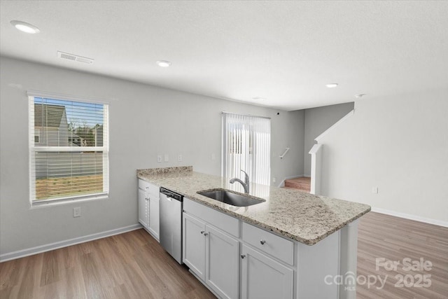 kitchen featuring sink, dishwasher, white cabinetry, light stone countertops, and kitchen peninsula