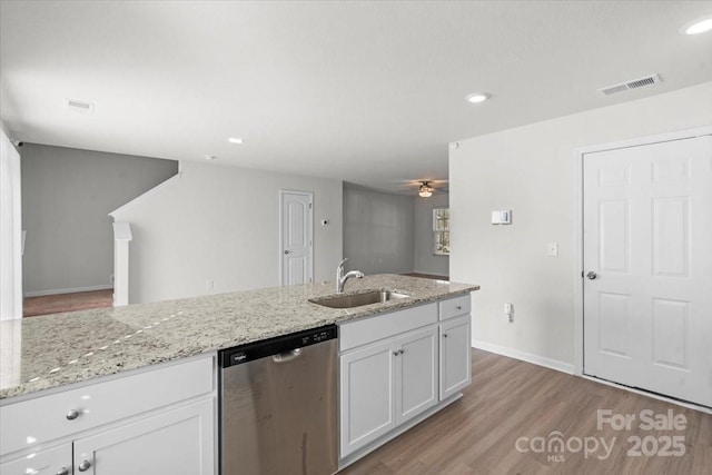 kitchen with dishwasher, sink, white cabinets, light stone counters, and light hardwood / wood-style flooring