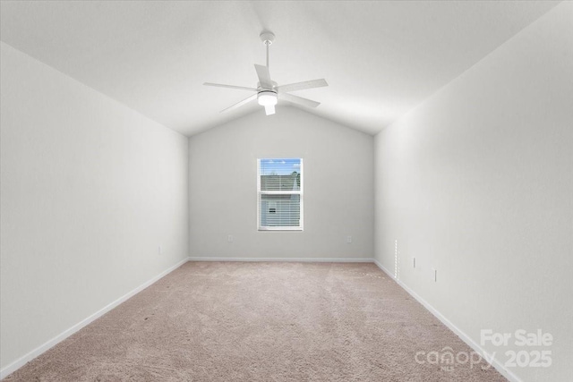 empty room featuring vaulted ceiling, light carpet, and ceiling fan