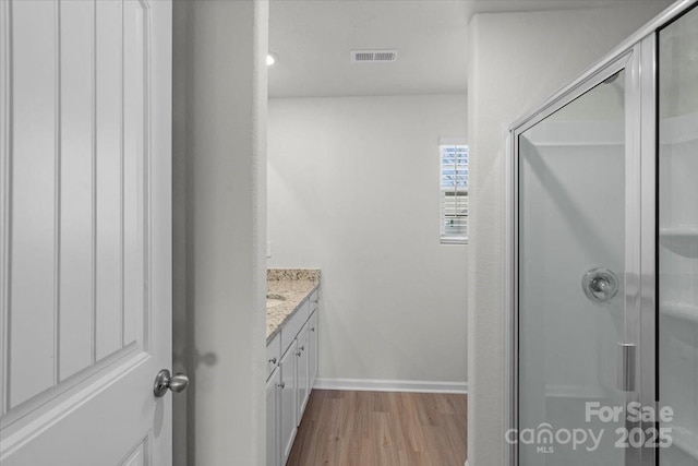 bathroom featuring vanity, wood-type flooring, and a shower with shower door