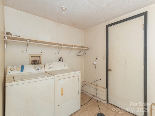 clothes washing area with light tile patterned floors, washer and dryer, and a textured ceiling