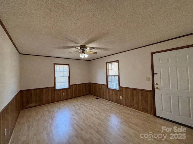 foyer entrance with ceiling fan, a wealth of natural light, a textured ceiling, and light wood-type flooring