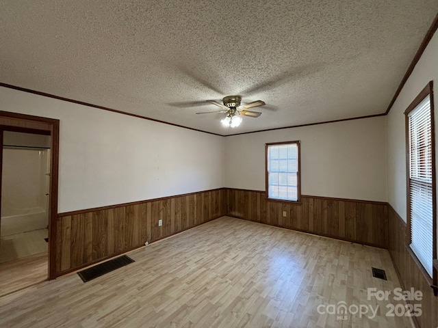 spare room featuring ceiling fan, crown molding, a textured ceiling, and light wood-type flooring