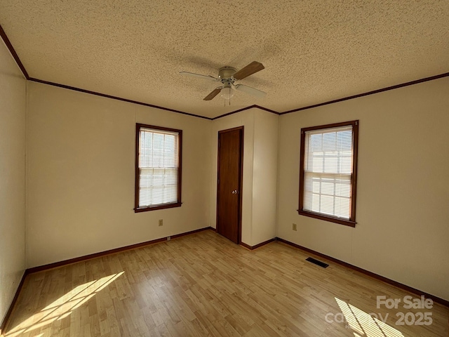 unfurnished bedroom with ornamental molding, ceiling fan, a textured ceiling, and light wood-type flooring