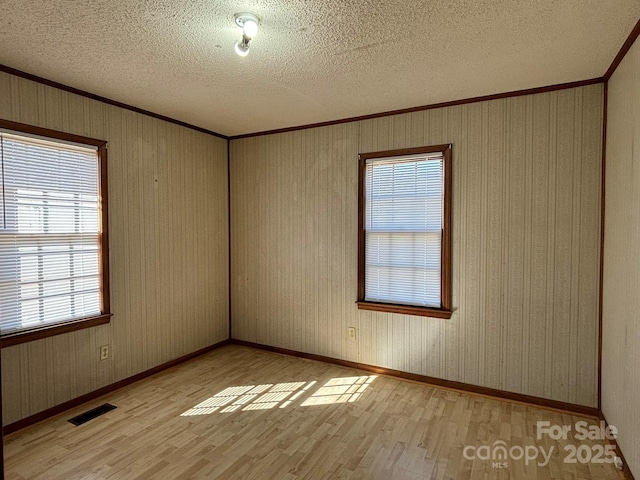 unfurnished room featuring crown molding, a textured ceiling, and light hardwood / wood-style floors