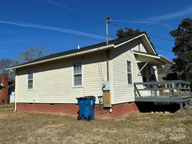 view of side of home with a wooden deck and a lawn