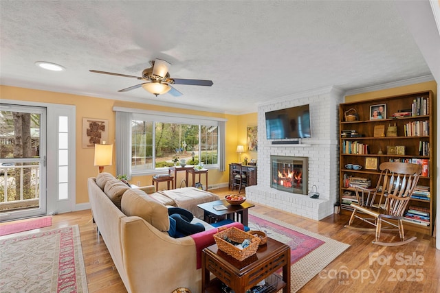 living room with ornamental molding, a fireplace, light hardwood / wood-style flooring, and a textured ceiling