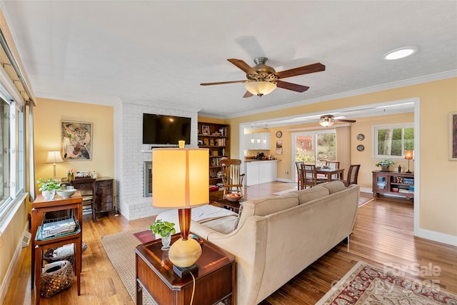 living room with crown molding, light hardwood / wood-style floors, and a brick fireplace