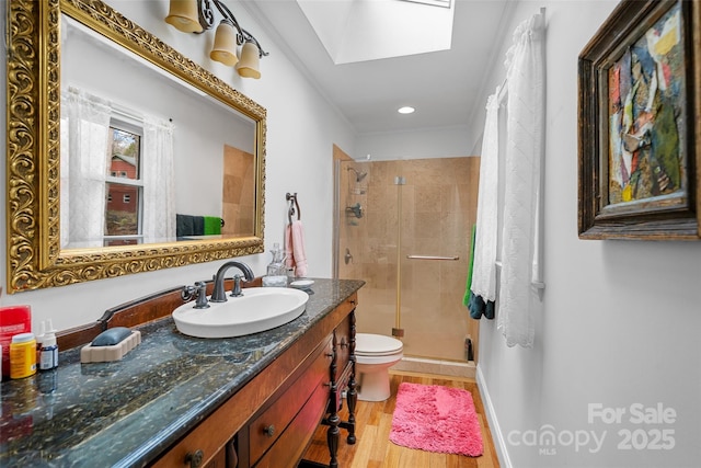 bathroom featuring toilet, a skylight, vanity, a shower with door, and hardwood / wood-style flooring