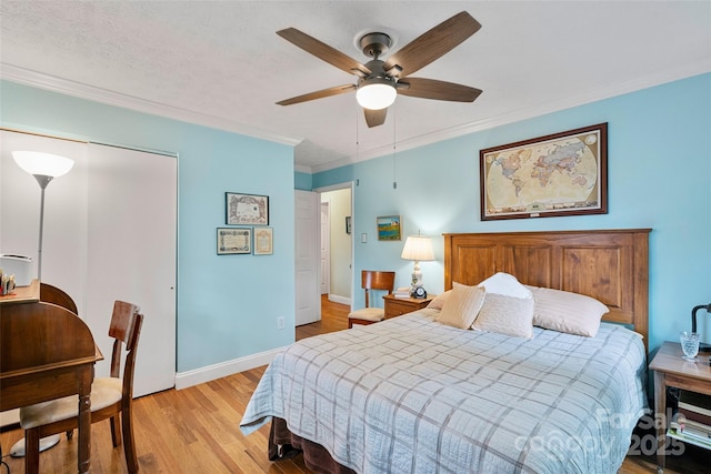 bedroom featuring light wood-type flooring, ornamental molding, ceiling fan, a textured ceiling, and a closet