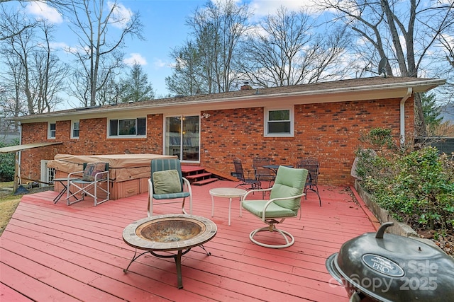 deck featuring an outdoor fire pit, a hot tub, and a grill