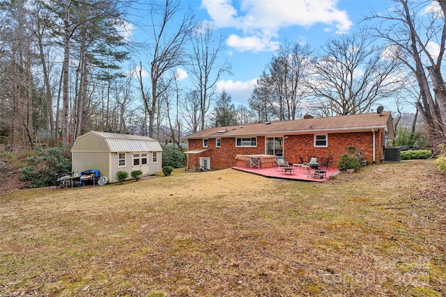 rear view of house featuring a shed, central AC unit, a yard, and a deck