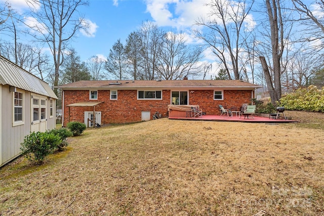 rear view of house with a yard, a hot tub, and a deck