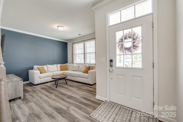 foyer with ornamental molding and light hardwood / wood-style floors