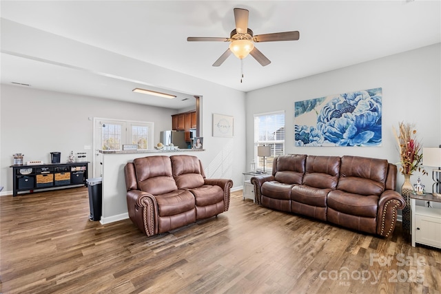 living room with a wealth of natural light, baseboards, and wood finished floors