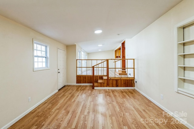 unfurnished room featuring light hardwood / wood-style floors and built in shelves