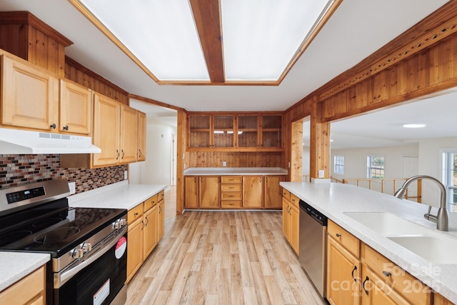 kitchen with sink, appliances with stainless steel finishes, light hardwood / wood-style floors, light stone countertops, and decorative backsplash