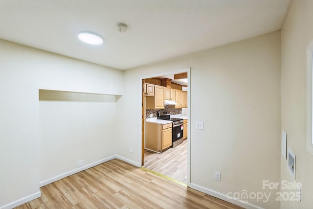 kitchen with stainless steel electric stove, light hardwood / wood-style flooring, and backsplash