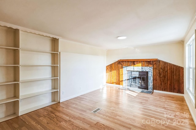 unfurnished living room featuring hardwood / wood-style flooring, a high end fireplace, and crown molding