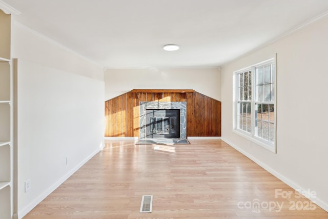 unfurnished living room with ornamental molding, a high end fireplace, and light wood-type flooring