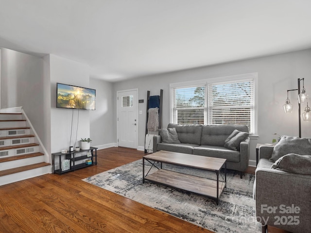 living area with dark wood-style flooring, stairway, and baseboards