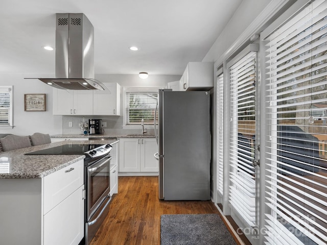 kitchen featuring light stone counters, island exhaust hood, stainless steel appliances, white cabinetry, and a sink