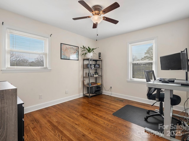 office space featuring dark wood-style floors, visible vents, baseboards, and a ceiling fan