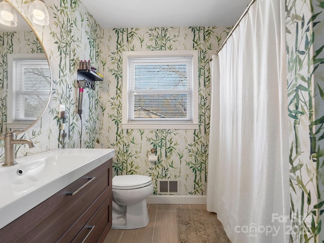 bathroom featuring toilet, baseboards, visible vents, and wallpapered walls