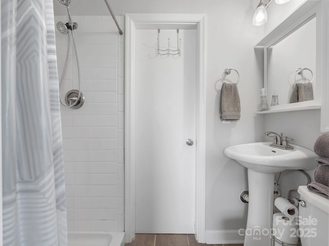 bathroom with a sink, a tile shower, and toilet