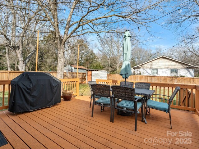 wooden terrace with a storage shed, outdoor dining space, area for grilling, and a fenced backyard