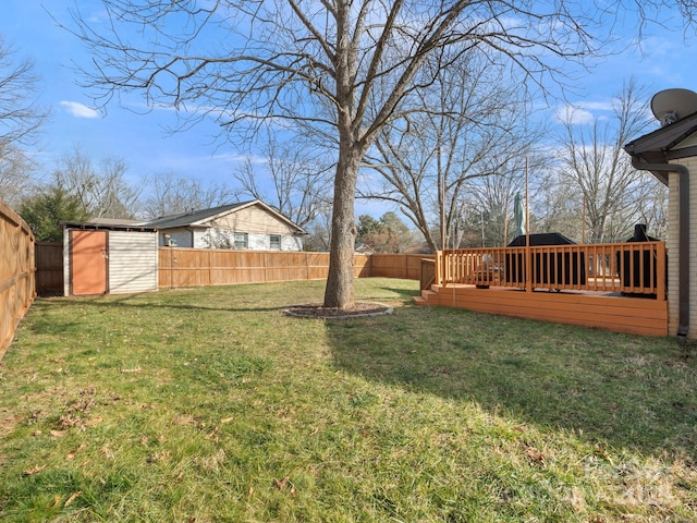 view of yard with an outbuilding, a storage unit, a fenced backyard, and a wooden deck