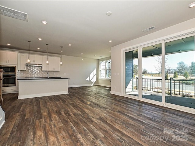 unfurnished living room with a water view, dark hardwood / wood-style floors, and sink