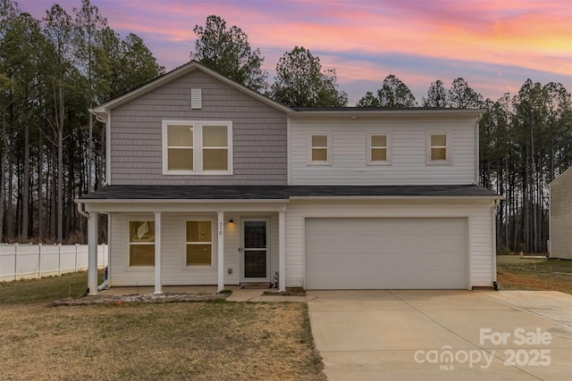 view of front of home with covered porch, a garage, fence, driveway, and a lawn