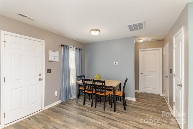 dining room featuring baseboards, visible vents, and wood finished floors
