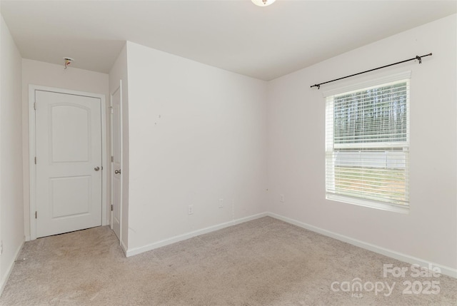 unfurnished room with light carpet and baseboards