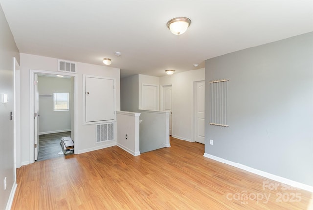empty room with light wood finished floors, baseboards, and visible vents