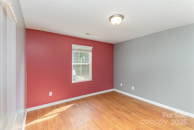 spare room featuring visible vents, baseboards, and wood finished floors