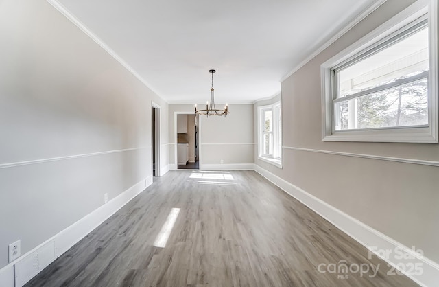 unfurnished dining area featuring crown molding, wood-type flooring, and a notable chandelier