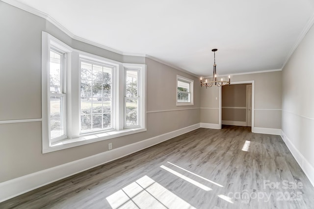 unfurnished dining area featuring an inviting chandelier, ornamental molding, and light wood-type flooring