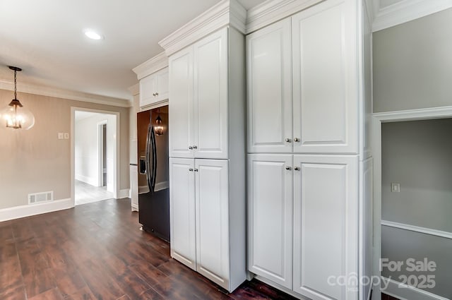 kitchen with white cabinetry, black fridge, dark hardwood / wood-style floors, and ornamental molding