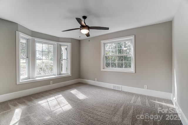 empty room featuring plenty of natural light, light colored carpet, and ceiling fan