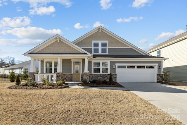 craftsman house featuring stone siding, covered porch, an attached garage, and concrete driveway