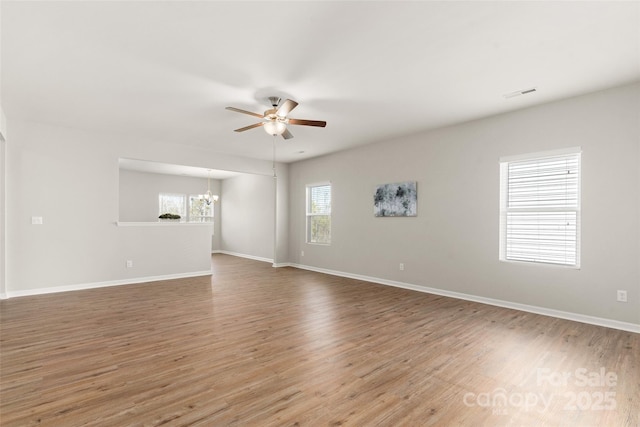 spare room with hardwood / wood-style flooring and ceiling fan with notable chandelier