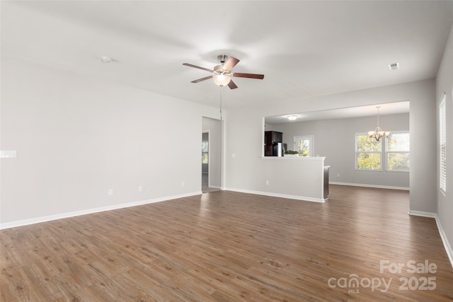 unfurnished living room featuring dark hardwood / wood-style flooring and ceiling fan with notable chandelier