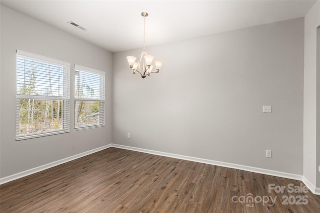 empty room with dark hardwood / wood-style flooring and a chandelier