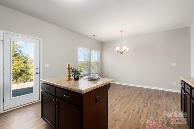 kitchen featuring an inviting chandelier, a center island, dark brown cabinets, hanging light fixtures, and light hardwood / wood-style floors