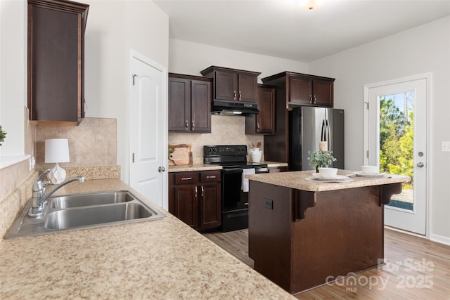 kitchen with a kitchen bar, sink, stainless steel refrigerator, black range with electric stovetop, and hardwood / wood-style floors