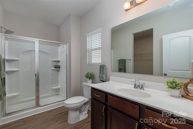 bathroom featuring hardwood / wood-style flooring, toilet, vanity, and a shower with shower door