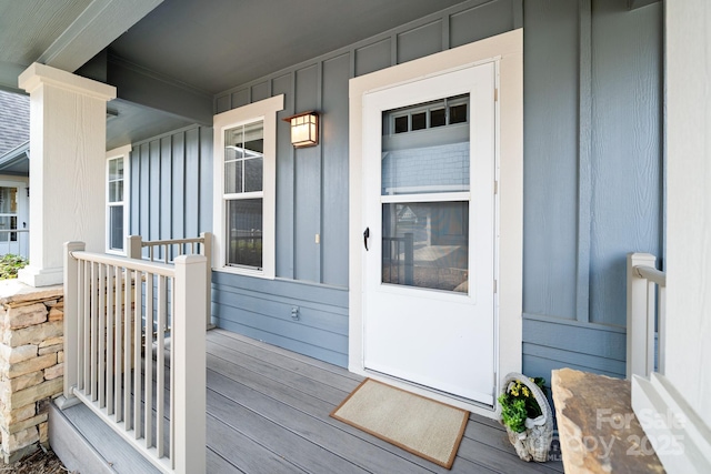 view of exterior entry with a porch and board and batten siding